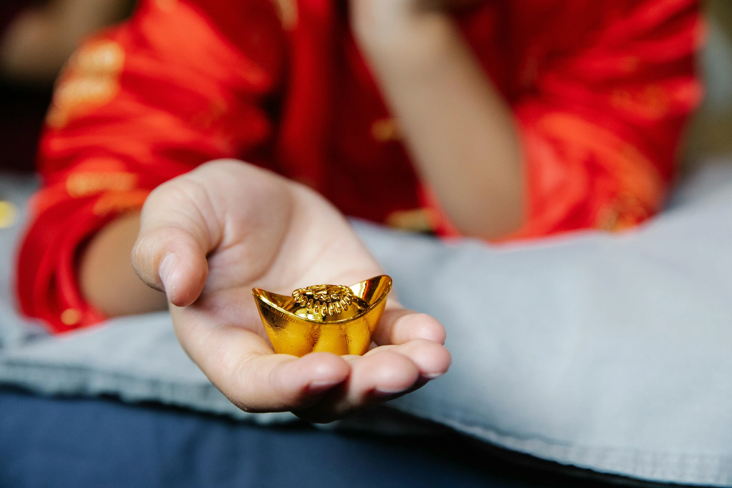 a close up of a person holding a gold ring, by Julia Pishtar, trending on unsplash, cloisonnism, floating chinese lampoons, sitting on a sofa, lump of native gold, mini model