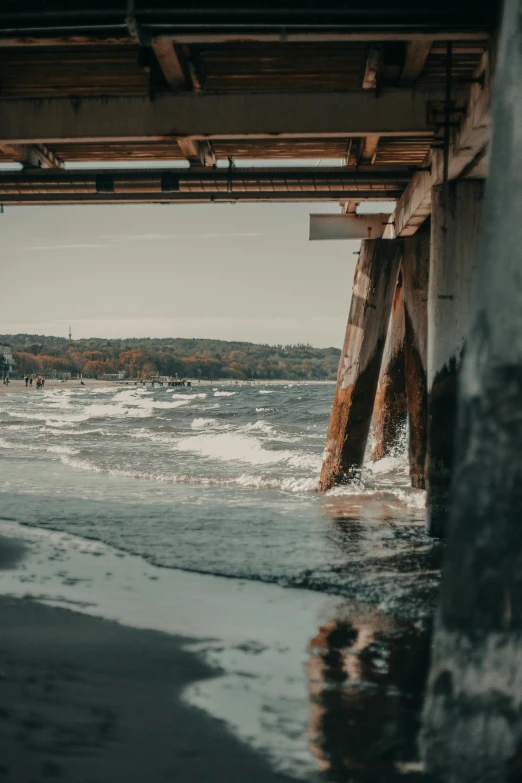 a wooden bridge over a body of water, a picture, pexels contest winner, rough waves, sitting under bridge, low quality photo, crumbling