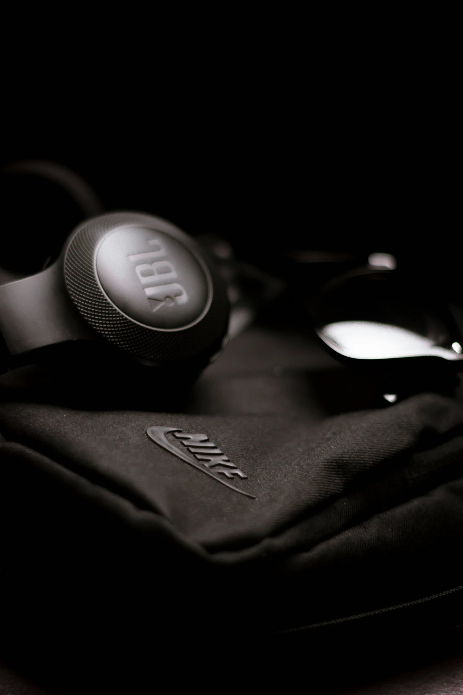 a pair of headphones sitting on top of a bag, black on black, mike