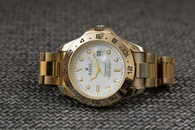 a close up of a watch on a table, a portrait, by Kev Walker, rolex, gold and white, taken in the late 2010s, realistic »