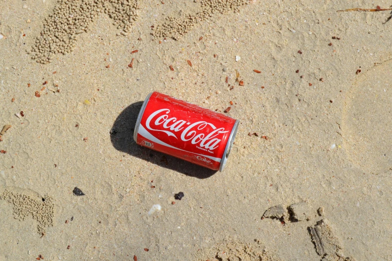 a can of coca cola laying in the sand, 2010s, fan favorite, debris