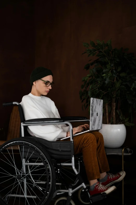 a man in a wheelchair using a laptop, a portrait, by Julia Pishtar, trending on pexels, androgynous person, 15081959 21121991 01012000 4k, wide full body, genderless