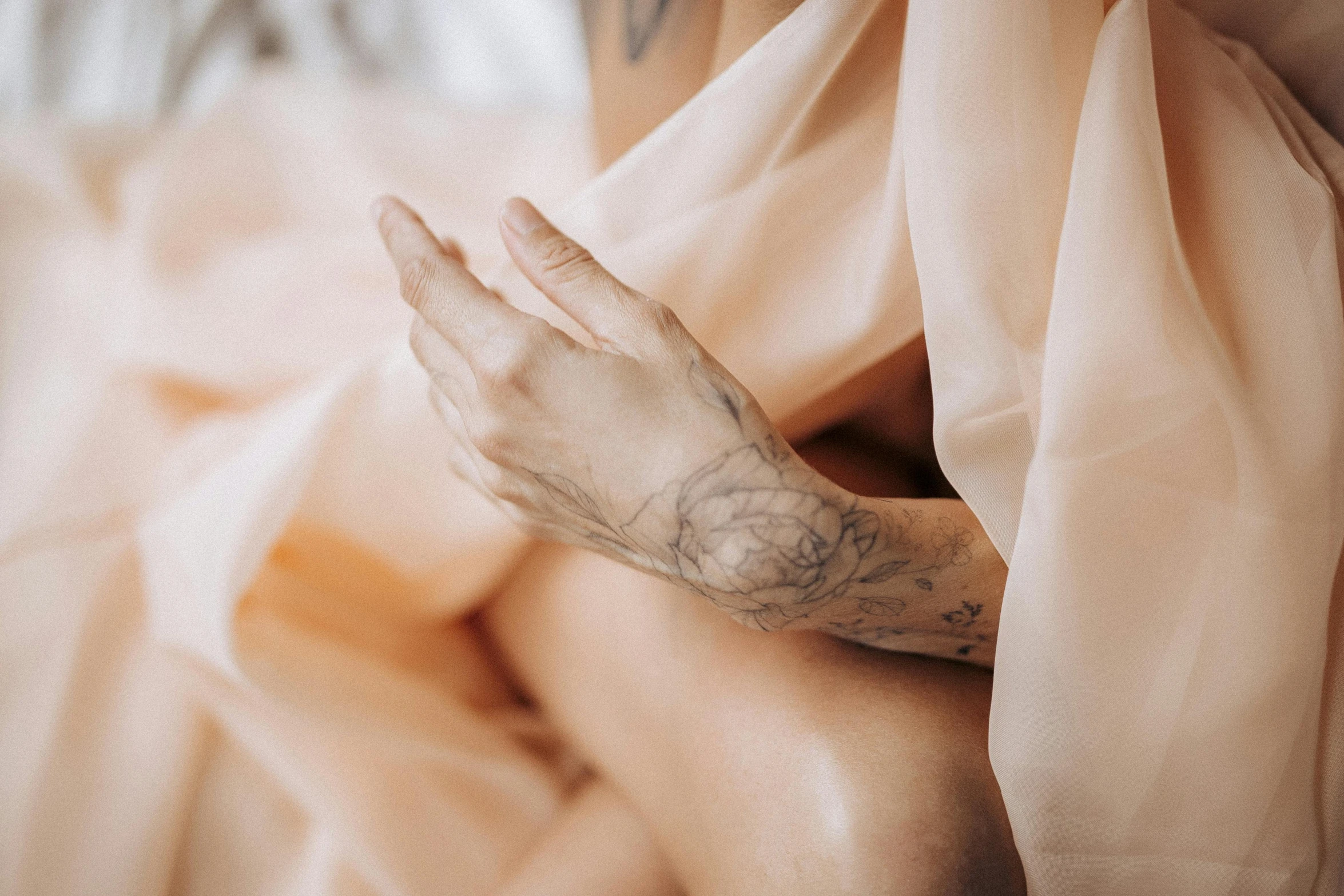 a woman with a tattoo on her arm, a tattoo, by Emma Andijewska, trending on pexels, aestheticism, pastel pink robes, figure meditating close shot, flowing silk sheets, holding hands