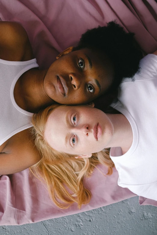 a couple of women laying on top of a bed, trending on unsplash, renaissance, heterochromia, diverse faces, julia garner, trans rights