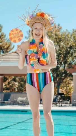 a woman standing next to a swimming pool, a colorized photo, inspired by Bunny Yeager, unsplash, lisa frank style, celebration costume, made of lollypops, high quality photo