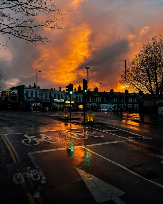 a traffic light sitting on the side of a road, an album cover, by Adam Rex, pexels contest winner, dramatic storm sunset, on a wet london street, ((sunset)), burning clouds