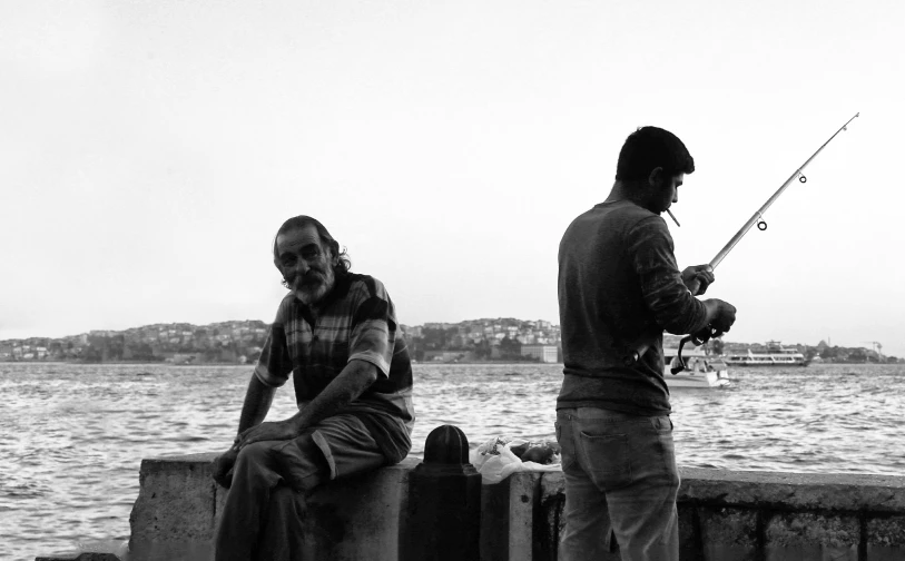 a black and white photo of two people fishing, a black and white photo, by Niyazi Selimoglu, fallout style istanbul, happy people, photographic print, low quality footage