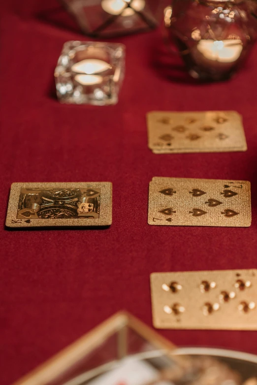 a table topped with cards and candles on top of a red table cloth, metallic brass accessories, zoomed in, spades slick, detailed product image