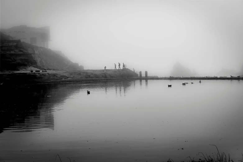 a black and white photo of a foggy lake, a black and white photo, by Josh Bayer, pexels contest winner, distant hooded figures, san francisco, ducks, oceanside