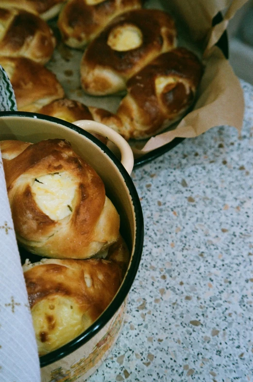 a box of buns sitting on top of a table, inspired by Géza Dósa, unsplash, hurufiyya, melted cheese, pot, curved, sweden