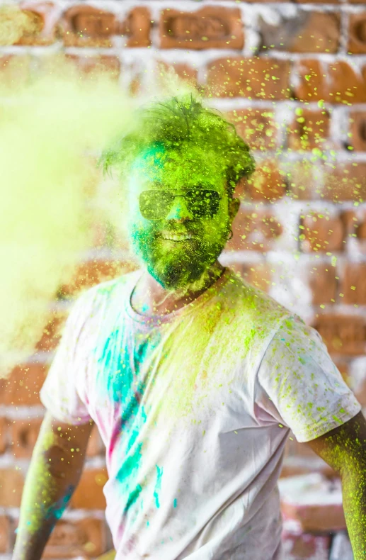 a man standing in front of a brick wall covered in green powder, cheerful colours, blurred face, scruffy man, splattered goo