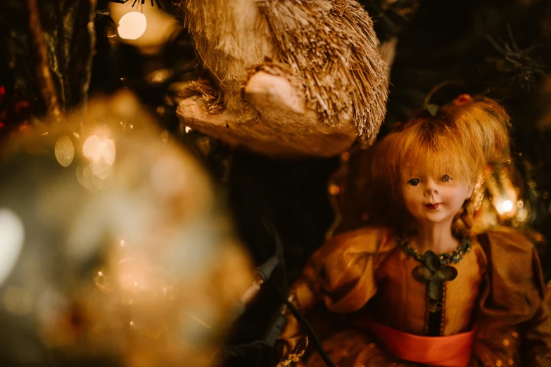 a close up of a doll on a christmas tree, a portrait, by Emma Andijewska, pexels contest winner, folk art, inside an old magical shop, golden glow, shot on sony a 7 iii, medium shot of two characters