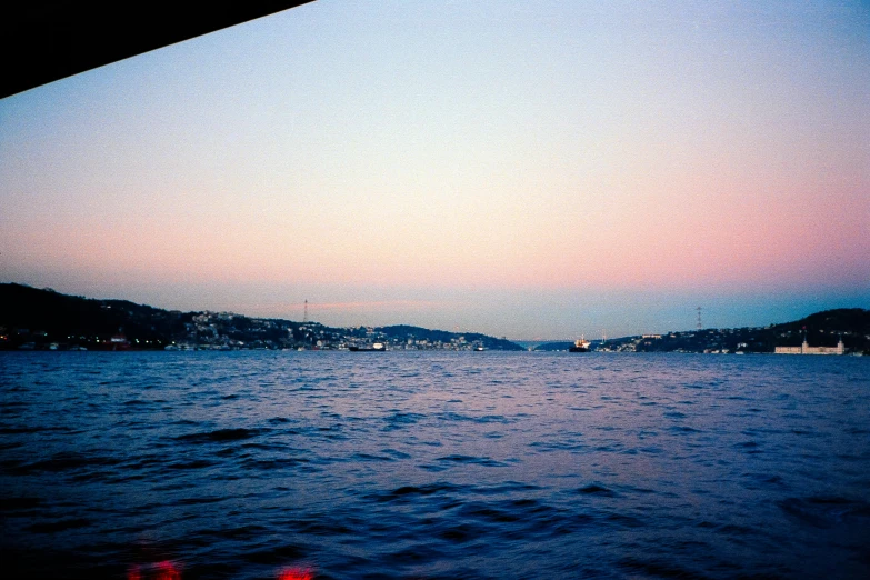 a view of a body of water from a boat, inspired by Elsa Bleda, hurufiyya, istanbul, 90's photo, early evening, shades of pink and blue