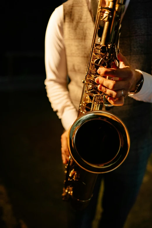 a man in a vest holding a saxophone, pexels, photorealism, softly lit, (night), premium quality, jazz album cover
