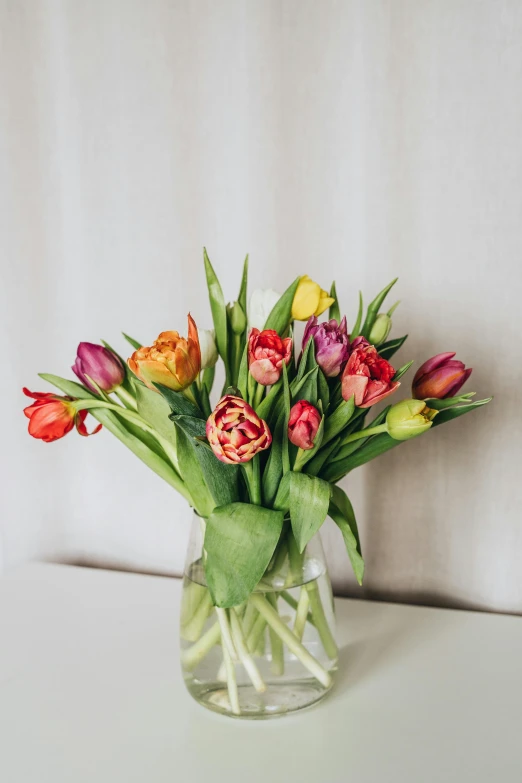 a vase filled with lots of flowers sitting on a table, tulips, full product shot, vibrant muted colors, highly polished