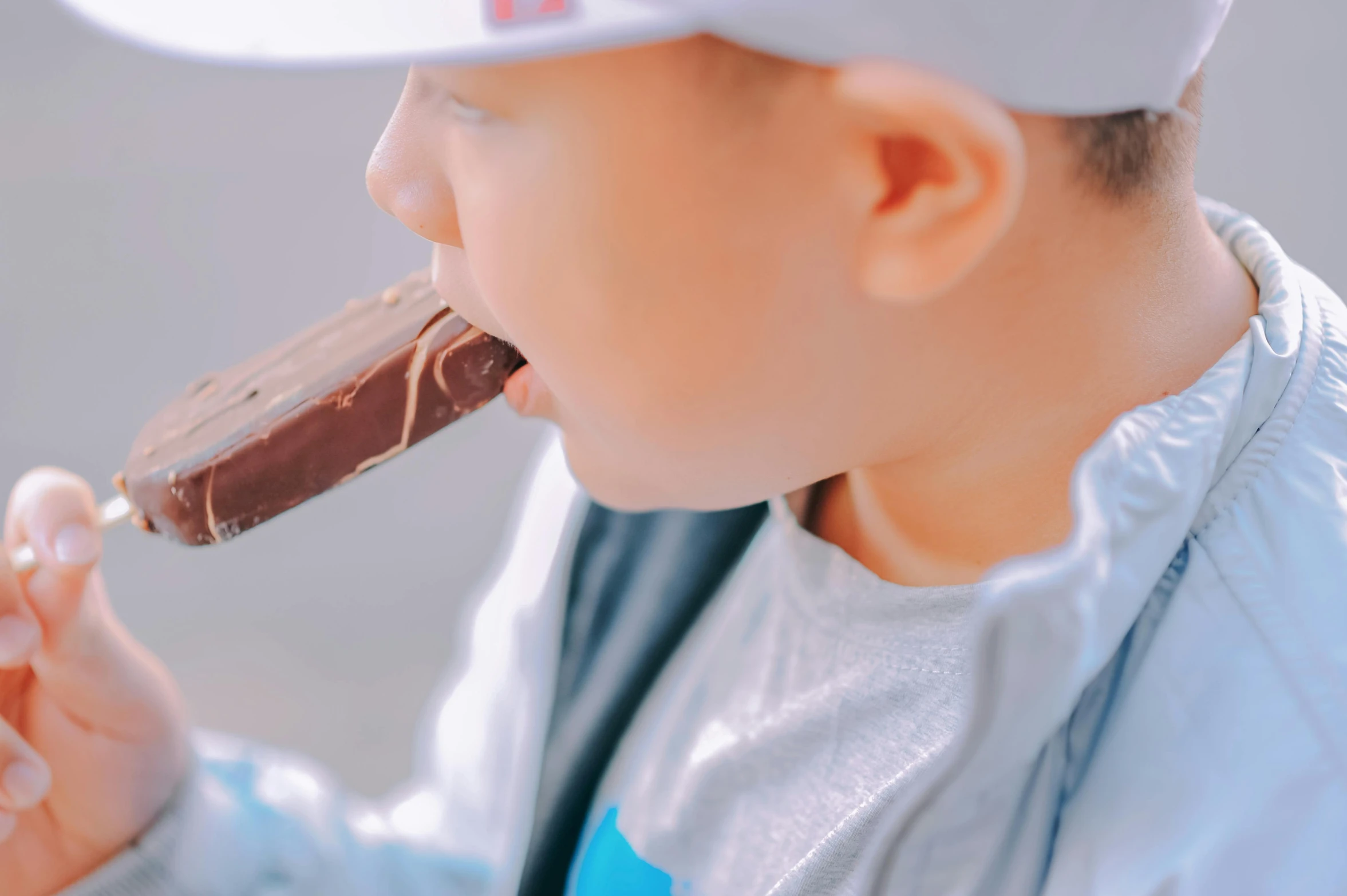 a young boy eating a chocolate covered ice cream bar, pexels contest winner, close up shot from the side, longque chen, lachlan bailey, profile image