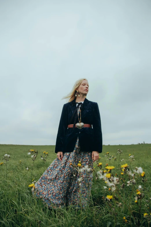 a woman standing in a field of flowers, an album cover, liz truss, wearing jacket and skirt, looking to the side off camera, prairie