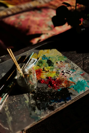 a close up of paint and brushes on a table, inspired by Pollock, trending on pexels, stands at a his easel, palettes, deep colour, model painting