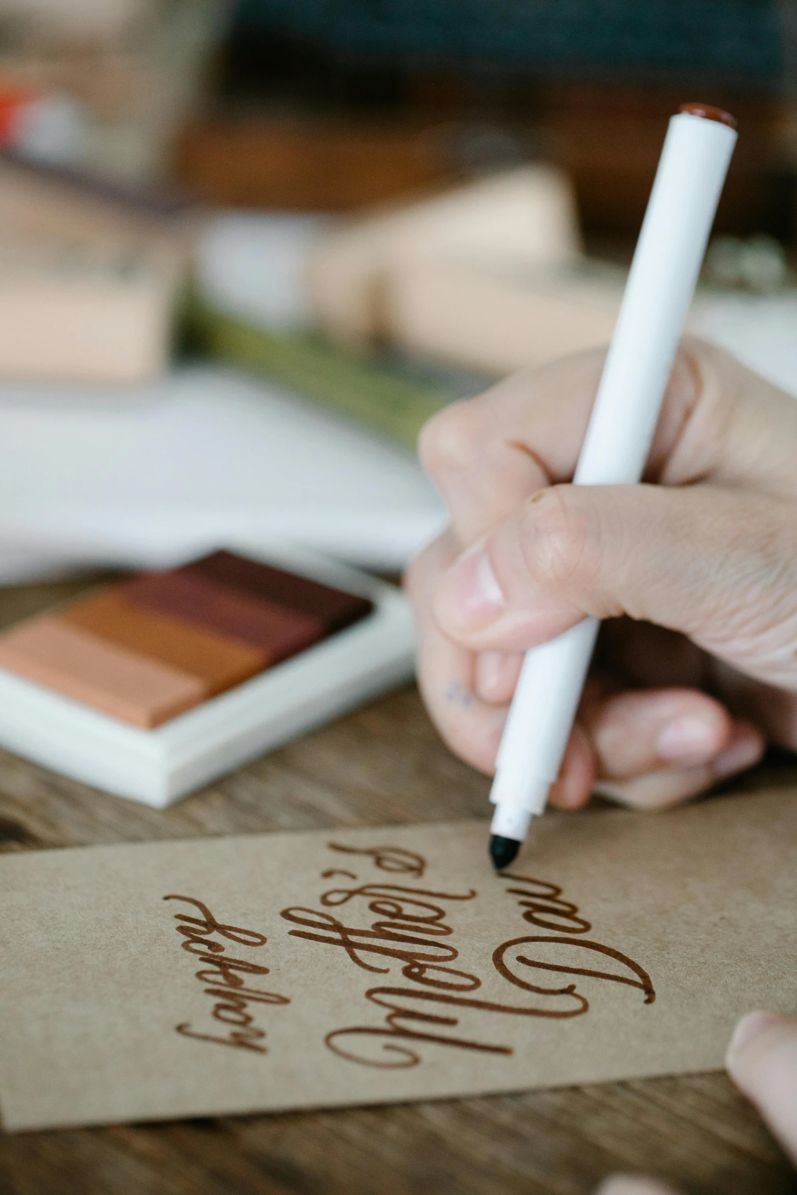 a close up of a person writing on a piece of paper, brown and white color scheme, packaging, caligraphy, thumbnail