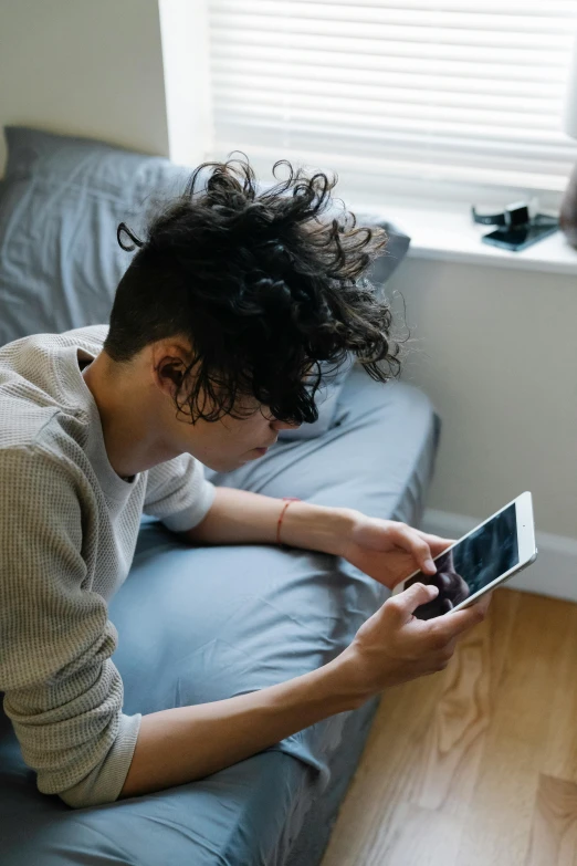 a person laying on a bed using a cell phone, trending on pexels, happening, curly and short top hair, lgbtq, boy has short black hair, ignant