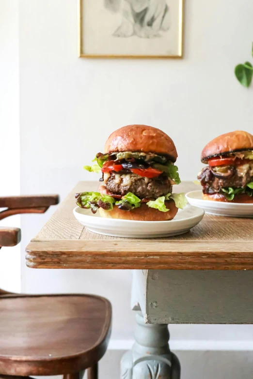 two burgers sitting on top of a wooden table, dwell, jen atkin, profile image, large)}]