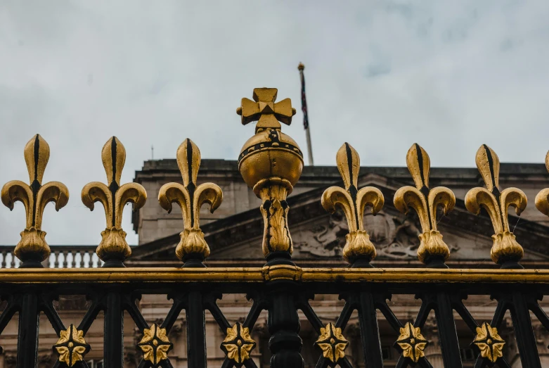 a close up of a fence with a building in the background, pexels contest winner, baroque, gold crown, thumbnail, in london, royal robe