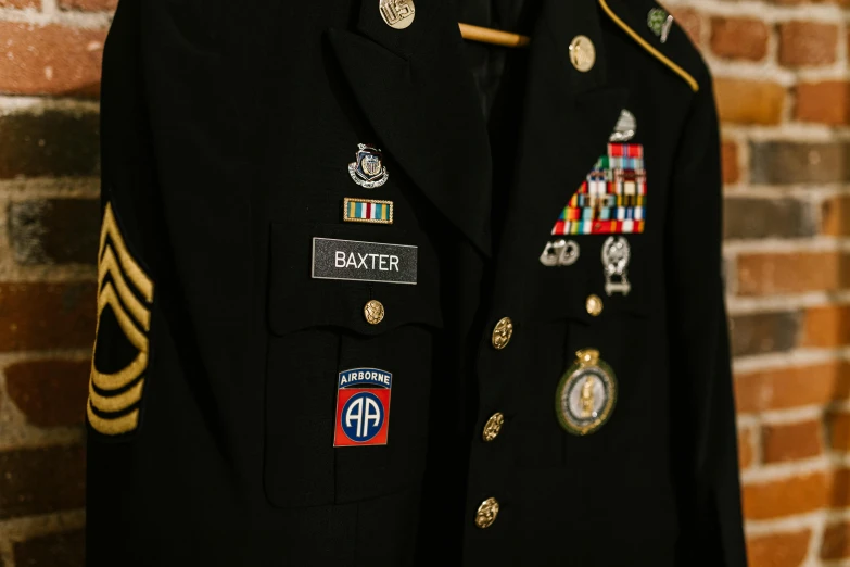 a military uniform hangs on a brick wall, by David Garner, pexels, embroidered robes, black, high school badge, neil leifer