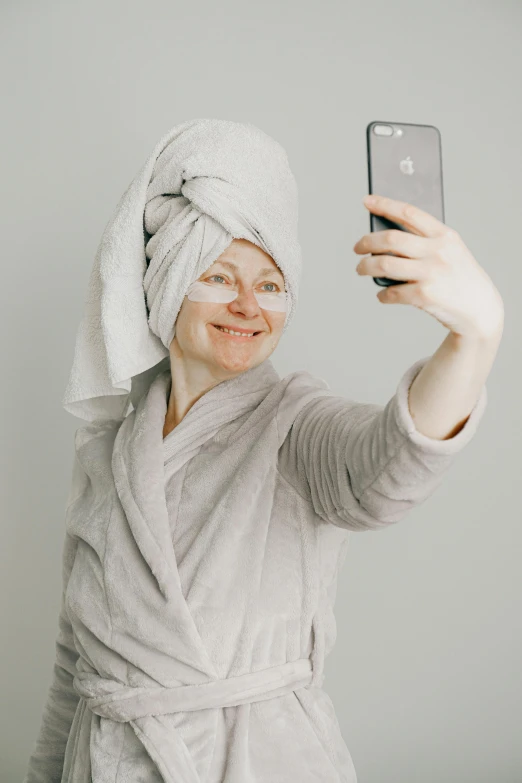 a woman with a towel wrapped around her head taking a selfie, trending on pexels, renaissance, grey, shaven, silicone skin, aged