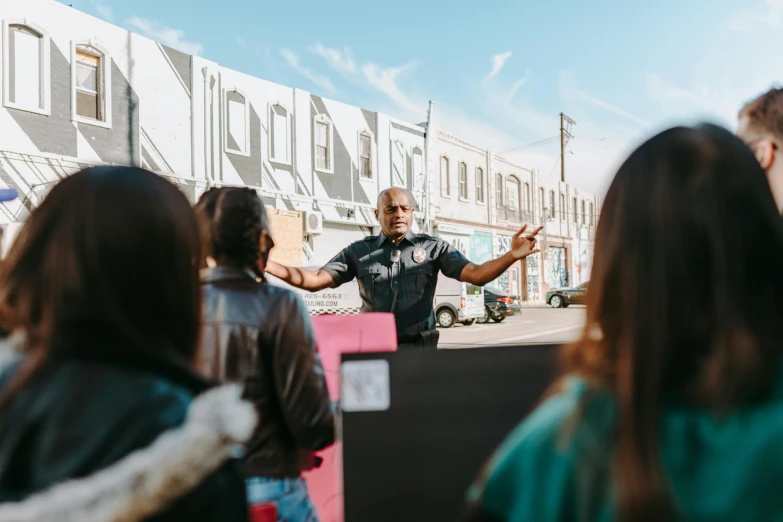 a man standing in front of a crowd of people, pexels contest winner, black arts movement, teaching, in an urban setting, bay area, background image