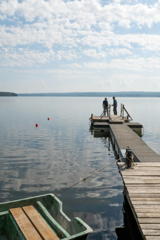 a couple of boats sitting on top of a lake, hurufiyya, quebec, small dock, people walking into the horizon, documentary photo