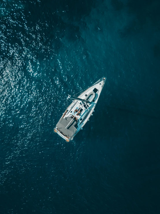 a boat in the middle of a body of water, top down, looking towards the camera, blue ocean, looking down on the camera