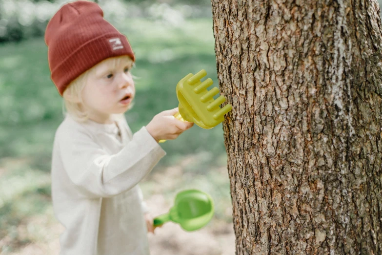 a little boy that is standing next to a tree, inspired by Elsa Beskow, unsplash, using a spade, detail shot, children's toy, sage green