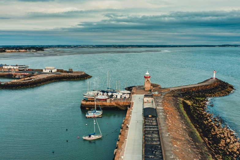 a group of boats sitting on top of a body of water, by Neil Boyle, pexels contest winner, maryport, wide high angle view, lighthouse, thumbnail