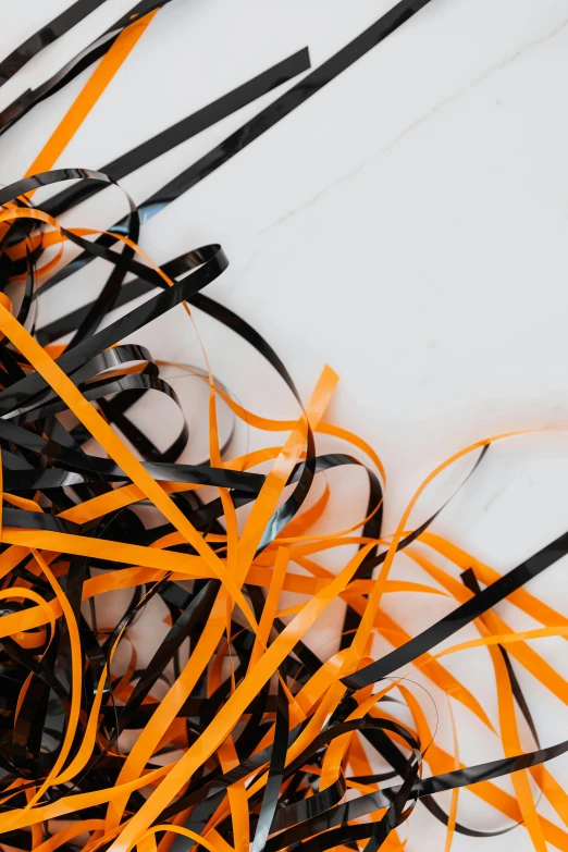 a pile of black and orange ribbons on a white surface, a cartoon, inspired by Christo, reddit, dynamic closeup, hay, paper cut art, dark filaments