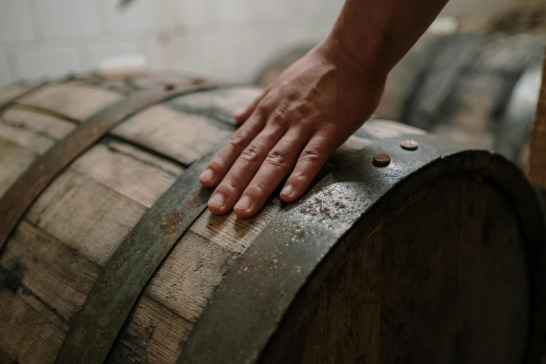 a close up of a person's hand on a barrel, background image, back towards camera, carefully crafted, hands on counter