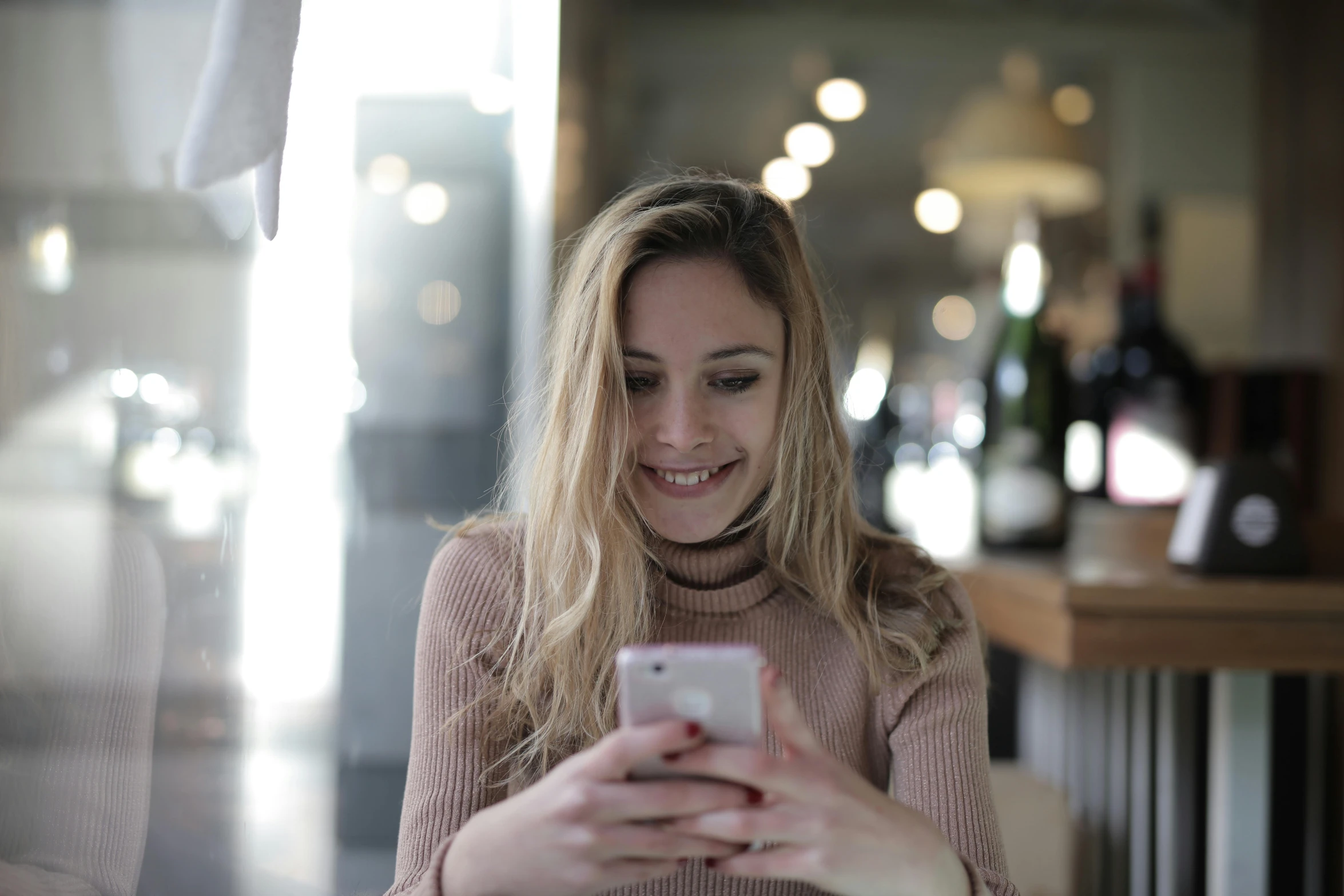 a woman sitting at a table looking at her cell phone, trending on pexels, smiling girl, alessio albi, a blond, gif