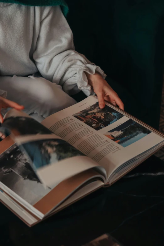 a person sitting on a couch reading a book, a picture, unsplash contest winner, science magazines, close up portrait photo, big opened book, 2019 trending photo