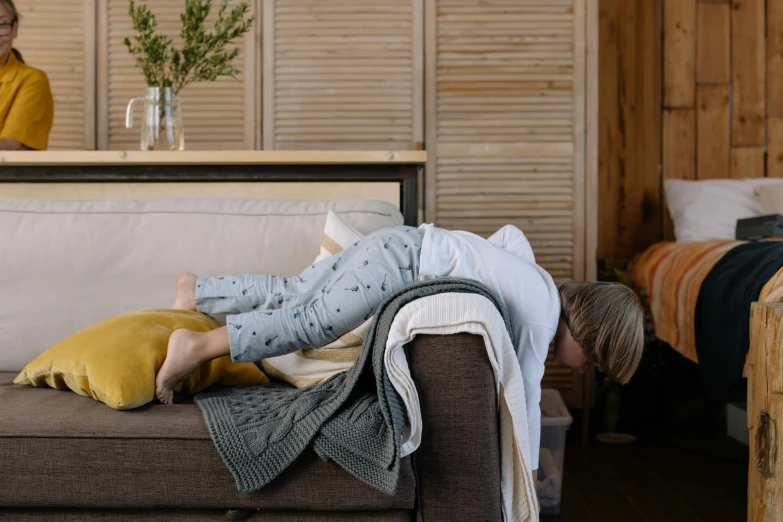 a woman laying on a couch in a living room, by Nina Hamnett, pexels contest winner, happening, head down, grey, family friendly, shot for pottery magazine