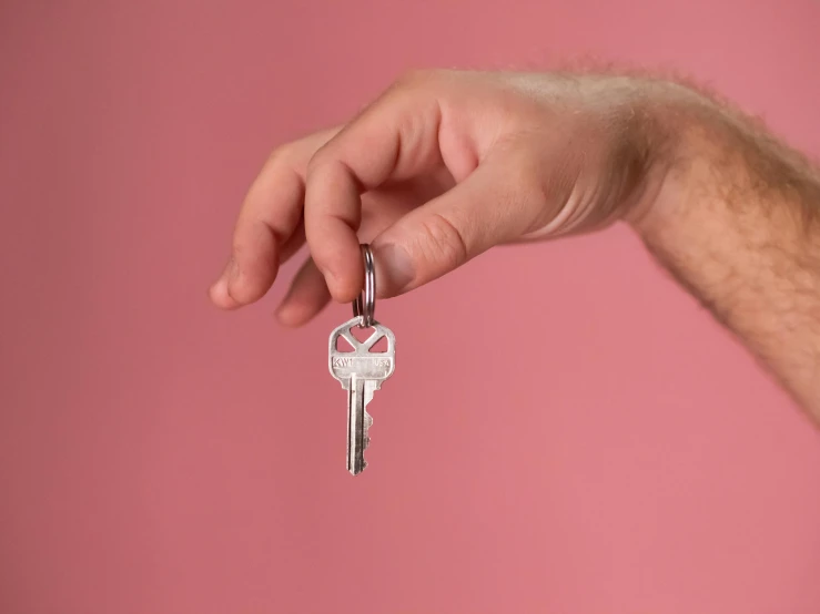 a person holding a key in their hand, an album cover, inspired by Cerith Wyn Evans, pexels contest winner, happening, pink studio lighting, airbnb, empty background, press shot