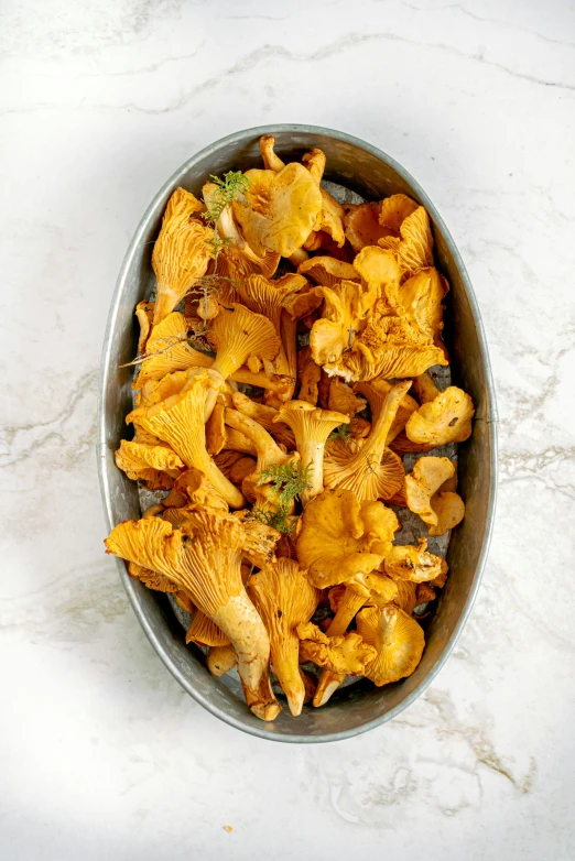 a pan filled with yellow mushrooms on top of a table, by Kristin Nelson, vibrant but dreary orange, gold flaked flowers, high quality product photo, single body