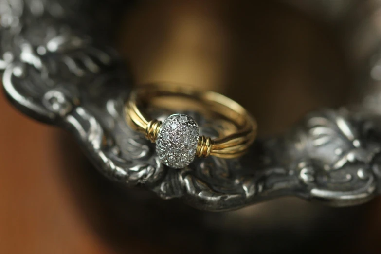 a couple of rings sitting on top of a silver bowl, gold wires, with sparkling gems on top, detailed product image, a wide shot