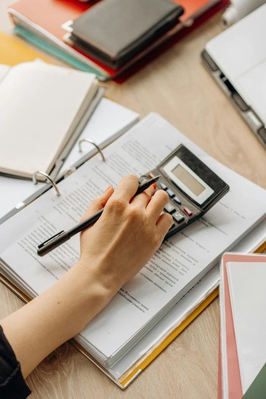 a person sitting at a table with a calculator, on a table