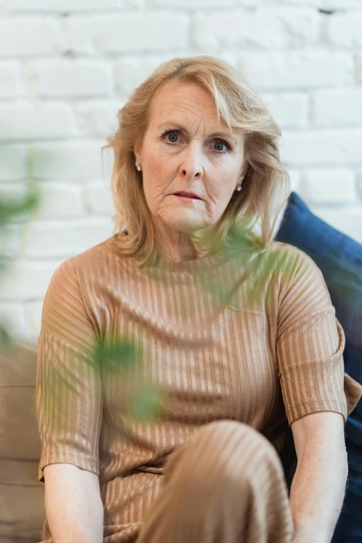 a woman sitting on a couch in a living room, by Grytė Pintukaitė, pexels, photorealism, looking confused, 5 5 yo, a full portrait of nordic female, promo photo