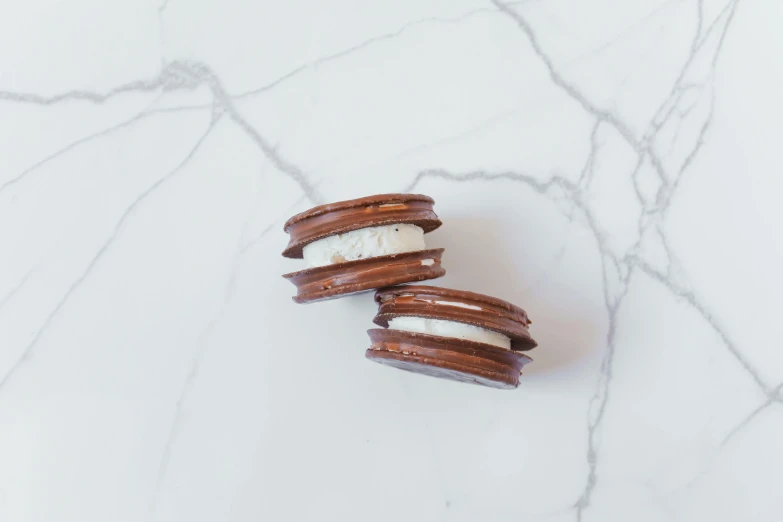 two chocolate covered ice cream sandwiches on a marble surface, unsplash, private press, macaron, 2 4 mm, s'mores, product view