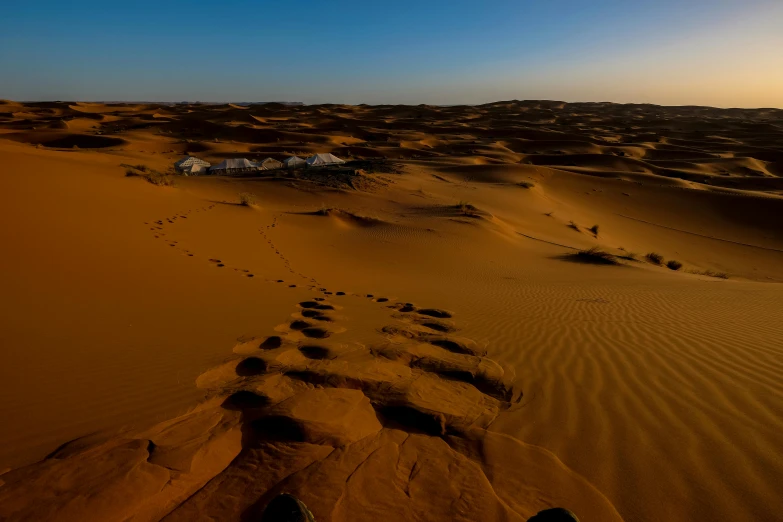 a person standing in the middle of a desert, pexels contest winner, les nabis, footprints, panoramic shot, tuareg, late evening