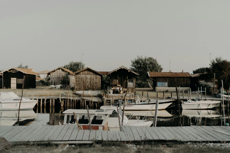 a number of boats in a body of water, by Anna Haifisch, pexels contest winner, rustic setting, side view from afar, portrait image, wooden structures
