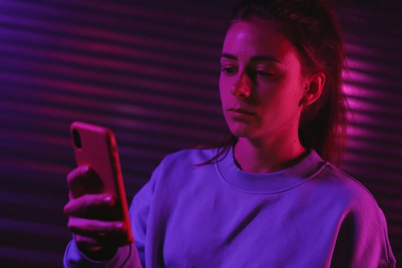 a woman is looking at her cell phone, inspired by Elsa Bleda, realism, purple neon, h3h3, serious lighting, teenage girl