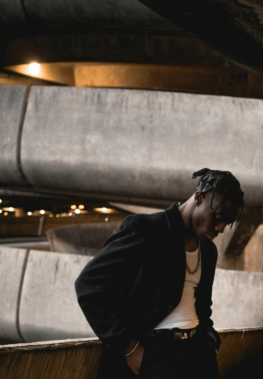 a man in a black jacket leaning against a wall, an album cover, by Winona Nelson, trending on unsplash, young thug, in a coliseum, thoughtful pose, ( ( dark skin ) )