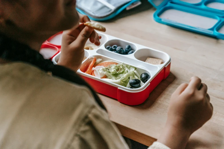 a person sitting at a table with a tray of food, pexels contest winner, plasticien, school class, red and white color theme, avatar image, healthy