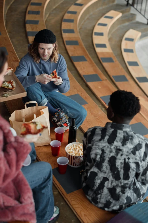 a group of people sitting around a table eating pizza, trending on pexels, hyperrealism, drive in movie theater, wearing jeans and a black hoodie, promotional image, university